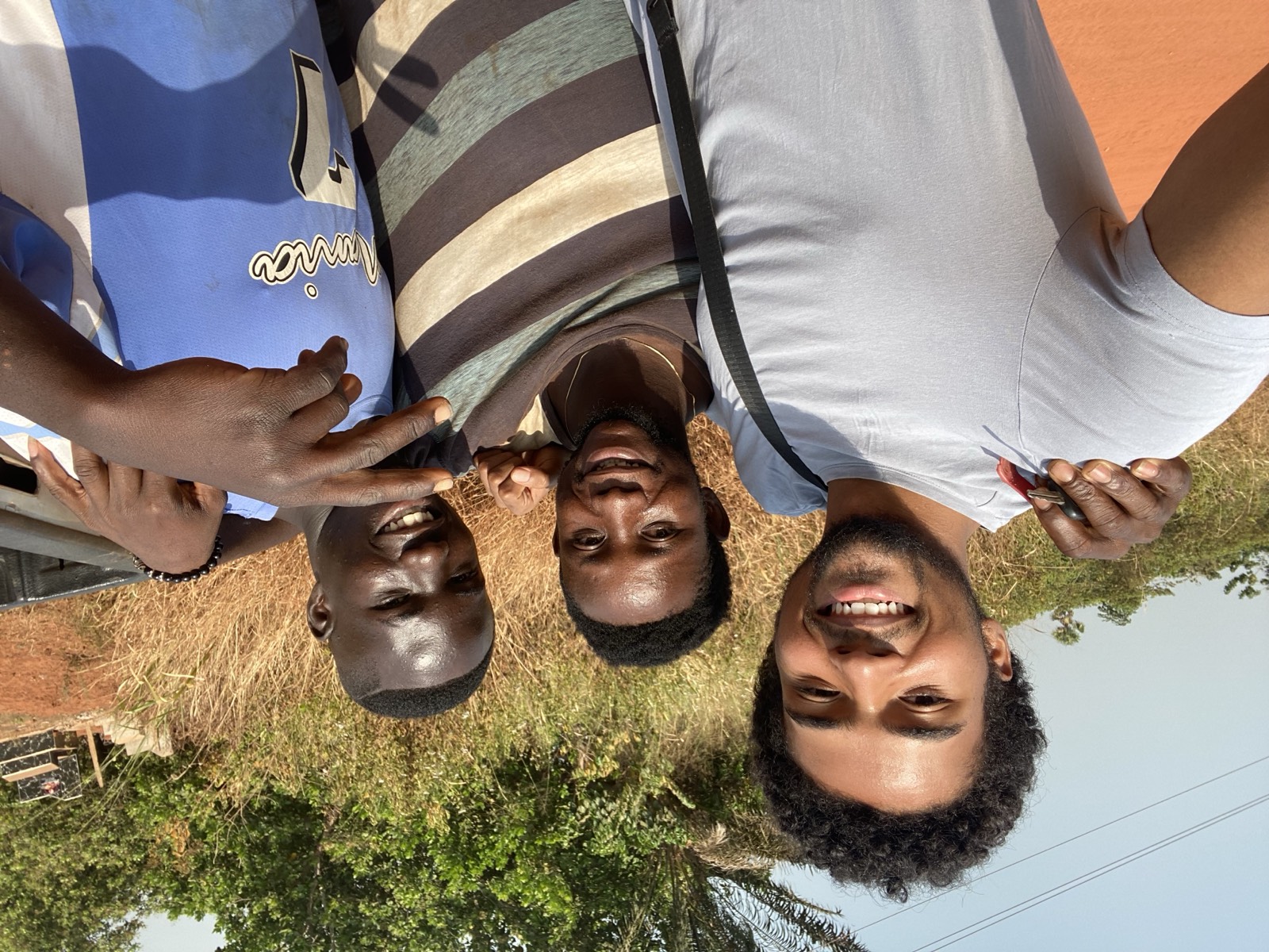 Kwame with two friends on a red dirt road outside Tuobodom