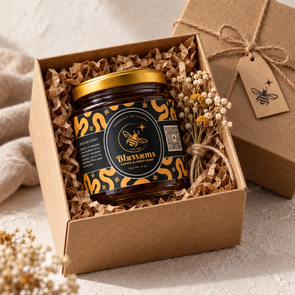 A jar of Blossoms honey nested in a kraft gift box with dried flowers